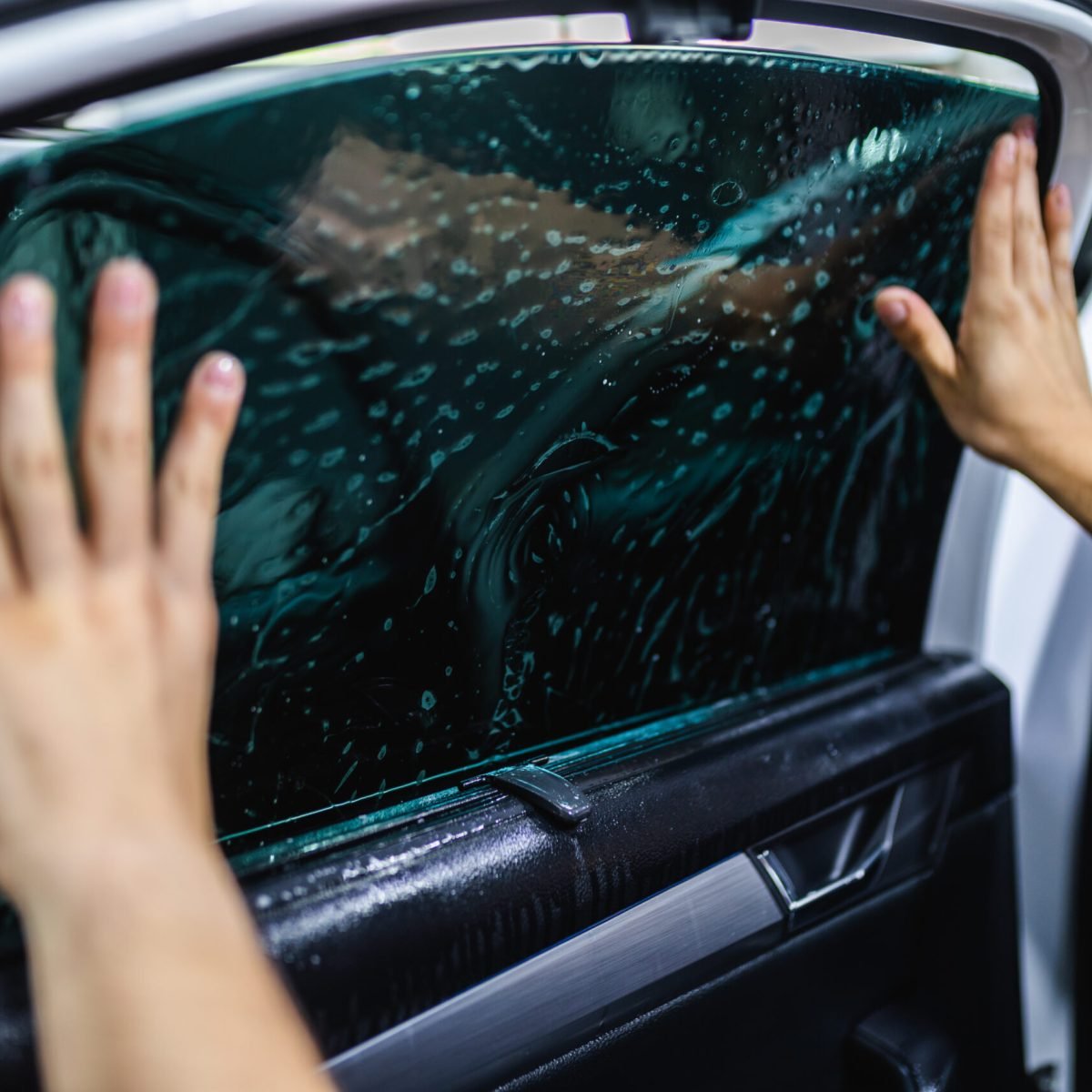 Car tinting – Worker applying tinting foil on car window. Car tinting - Worker applying tinting foil on car window.